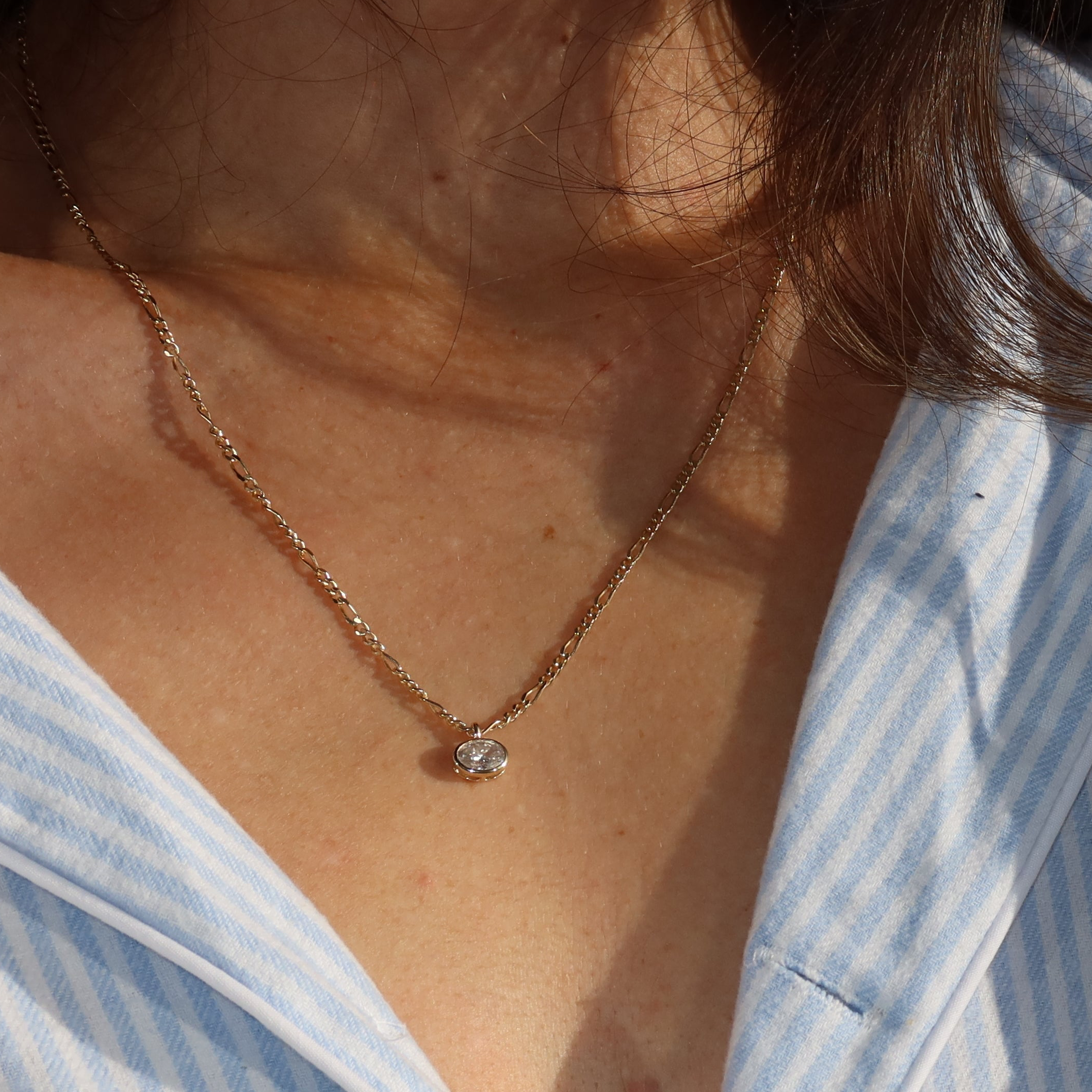 9 karat yellow gold figaro chain with alternating oval and round links worn with oval lab diamond pendant