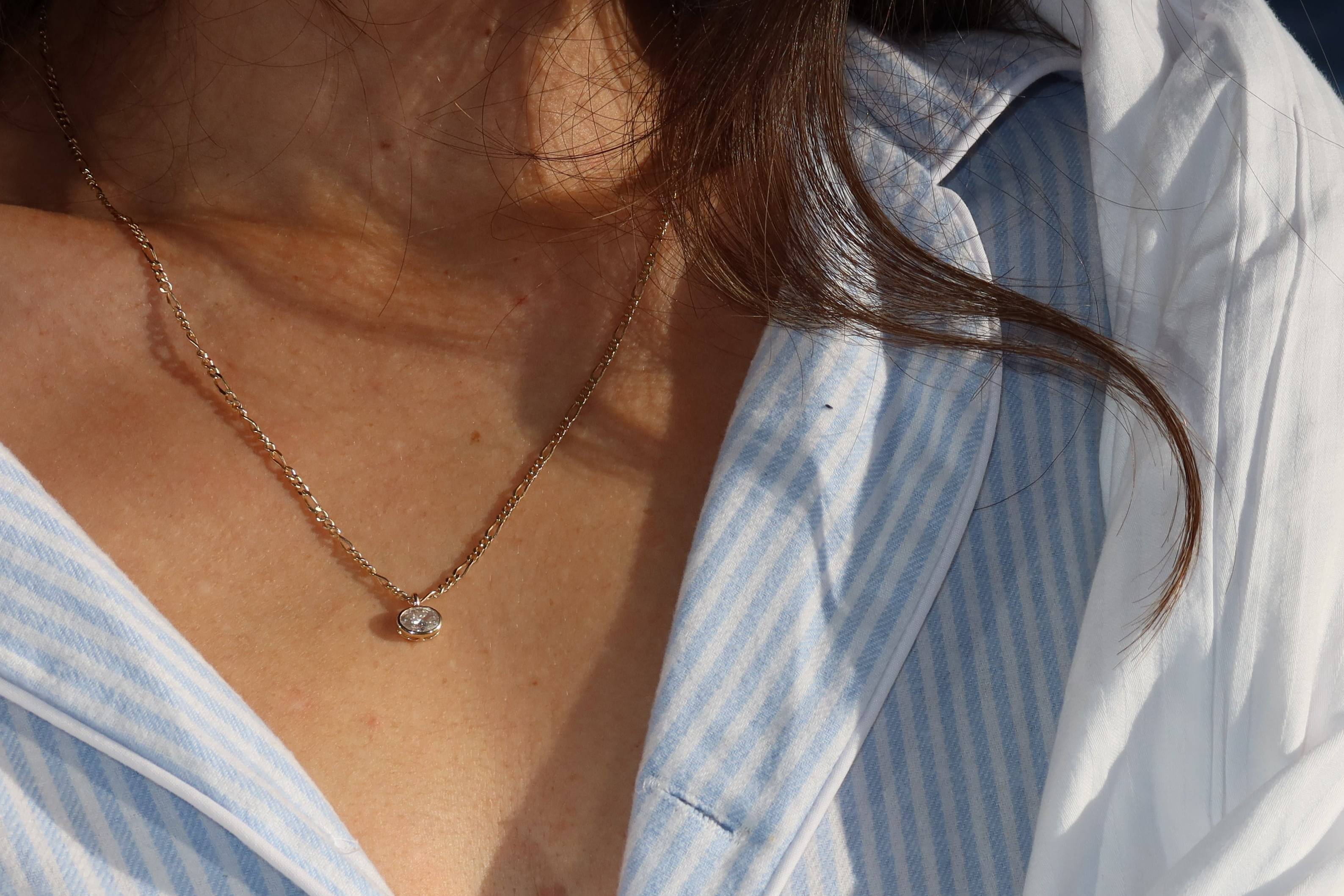 9 karat yellow gold figaro chain with alternating oval and round links worn with oval lab diamond pendant