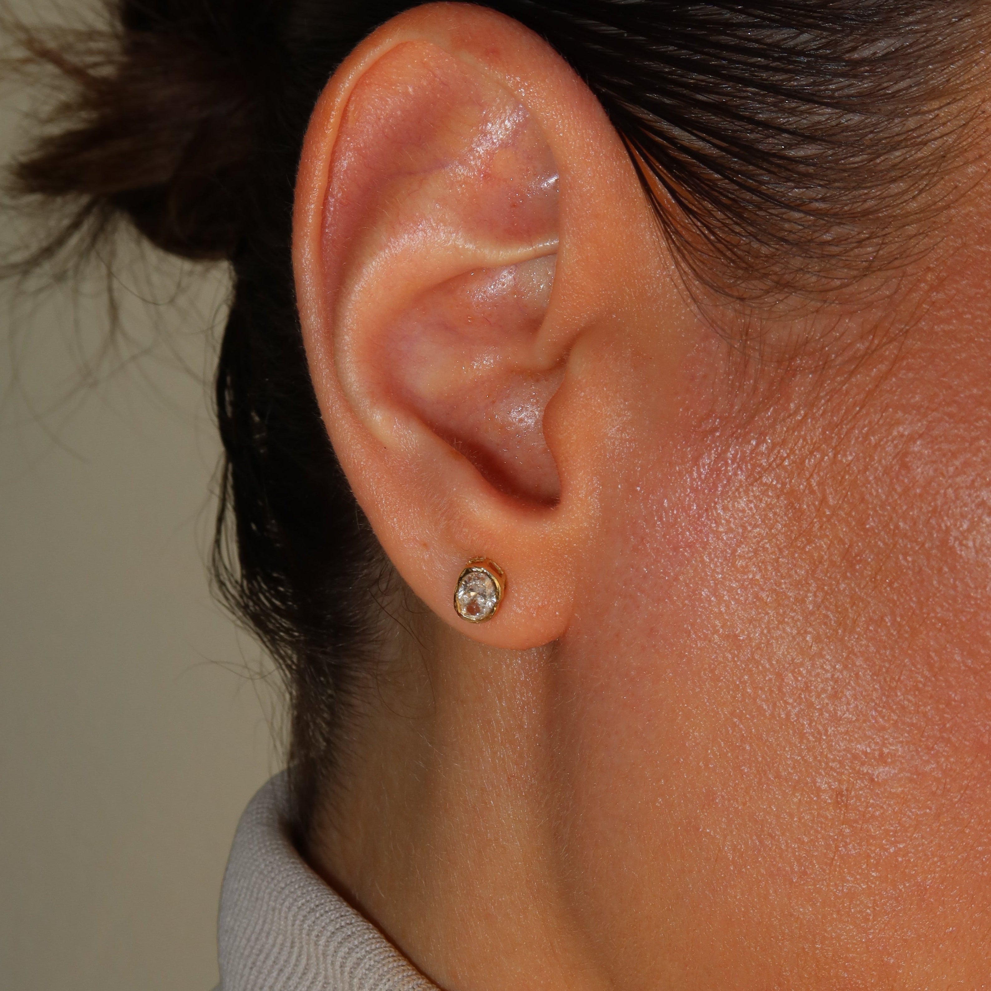 melted oval lab diamond stud earrings in 10 karat yellow gold on a female